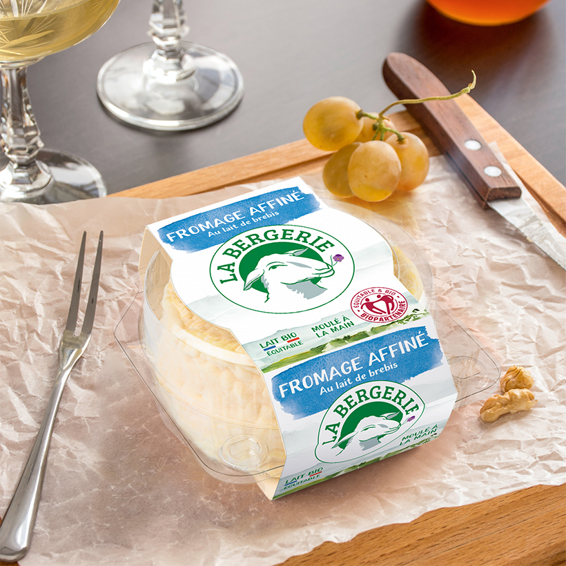 Instant de consommation fromage affiné La Bergerie, sur une table, avec un couteau, une fourchette et des grains de raisin